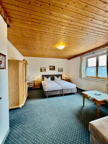 a bedroom with a large bed and a wooden ceiling at Pension Schweizerhaus Garni in Weyarn