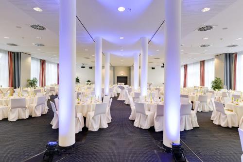 a banquet hall with white tables and chairs at Novina Hotel Herzogenaurach Herzo-Base in Herzogenaurach