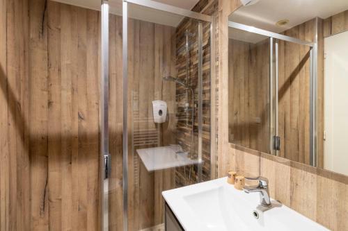 a bathroom with wooden walls and a sink and a shower at Hôtel Jean XXII in Cahors
