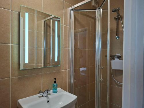 a bathroom with a sink and a shower with a mirror at Thurlestone House in St Ives
