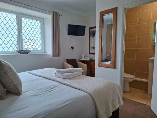 a white bedroom with a bed and a bathroom at Thurlestone House in St Ives