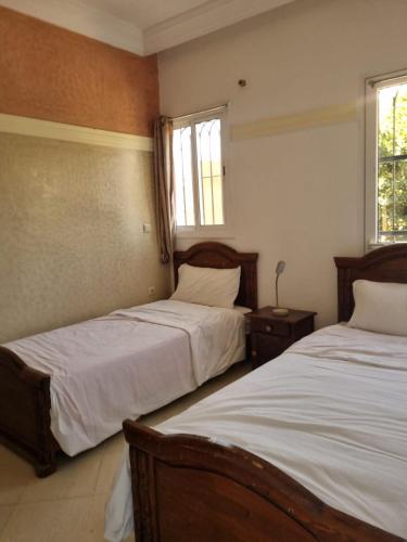 a bedroom with two beds and two windows at Appartement Imi-Ouaddar 1 in Agadir nʼ Aït Sa