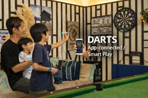 a man and two boys playing a video game at カラオケ ビリヤード 卓球 ダーツ バーベキュー 4寝室8ベッド16名可 読谷村 沖縄中部 in Yomitan