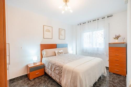 a white bedroom with a bed and a dresser at Euma Apartment in Cunit