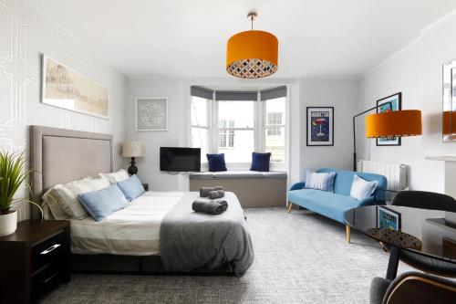a bedroom with a bed and a blue couch at CITY HEART BRIGHTON in Brighton & Hove