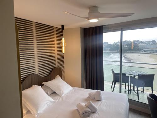 a bedroom with a bed with white pillows and a balcony at Best Western Hotel Le Crystal Dinard in Dinard