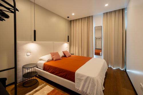 a bedroom with a large bed with orange and white sheets at Essence Villas - Garden & Spa in Ribeira Grande