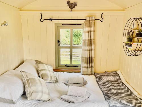 a white bed in a room with a window at Cwt Tyddyn Shepherd's Hut in Corwen