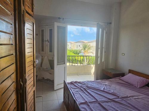 a bedroom with a bed and a door to a balcony at Modern Luxury Villa Steps from the Sea North Coast in Borg El Arab