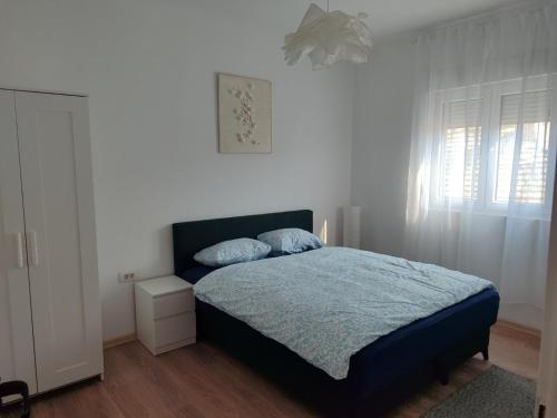 a bedroom with a bed with blue sheets and a window at Apartman Centar Surcin 2 in Surčin
