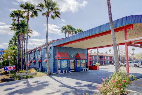 a building with palm trees in front of a street at Texas Inn Brownsville by Hotel O in Brownsville