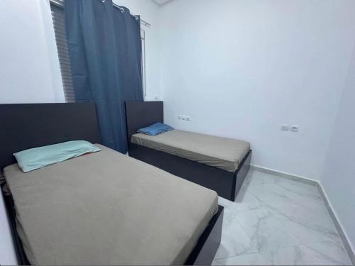 two twin beds in a room with a window at Appartement dans quartier calme in Agadir
