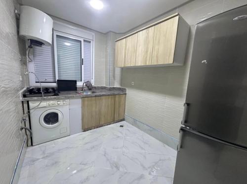 a kitchen with a refrigerator and a washer and dryer at Appartement dans quartier calme in Agadir