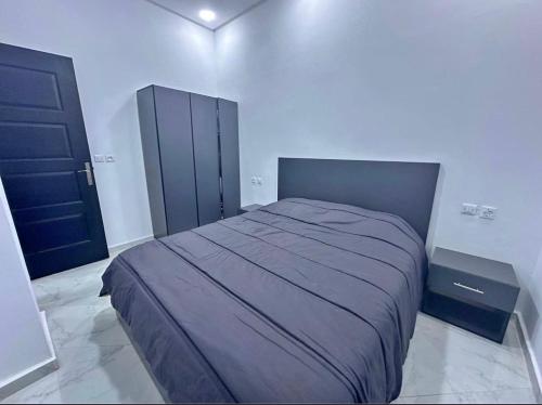 a bedroom with a bed and a black cabinet at Appartement dans quartier calme in Agadir
