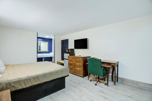 a bedroom with a bed and a desk with a computer at Texas Inn Brownsville by Hotel O in Brownsville