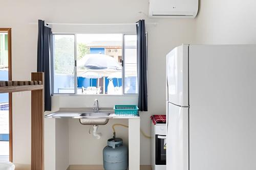 a kitchen with a sink and a refrigerator at Chalés do Mako in São Sebastião