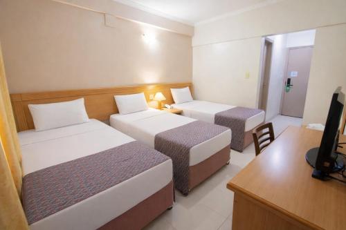 a hotel room with two beds and a desk at Hotel Dan Inn Express Ribeirão Preto By Nacional Inn in Ribeirão Preto