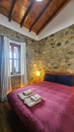 a bedroom with a large red bed in a stone wall at CasaLambra Pedoulas Exclusive Accomodation Troodos Mountains in Pedoulas