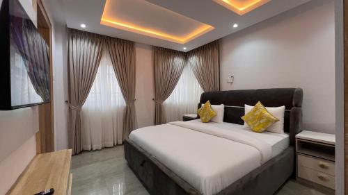 a bedroom with a large bed with yellow pillows at Hillgates Apartments Ikeja in Ikeja