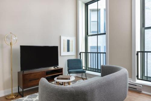 a living room with a tv and a couch and chairs at LIVN Millennium Park Downtown Chicago 1 BR in Chicago
