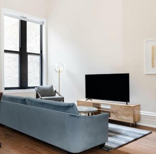 a living room with a large couch and a flat screen tv at LIVN Millennium Park Downtown Chicago Superior 2 BR in Chicago