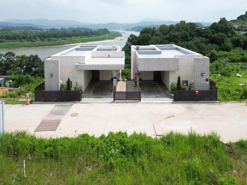 a large white building with a river in the background at Yeoncheon Bell 37 Pool Villa in Yeoncheon