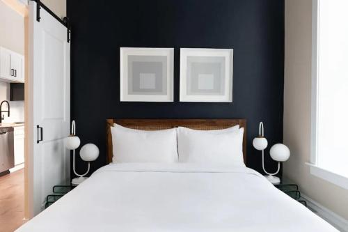 a bedroom with a white bed with two pictures on the wall at LIVN Millennium Park Downtown Chicago Superior 1BR in Chicago