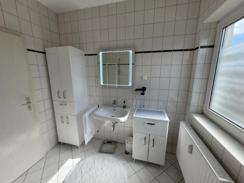 a white bathroom with a sink and a mirror at Ferienwohnung Bischof in Echzell