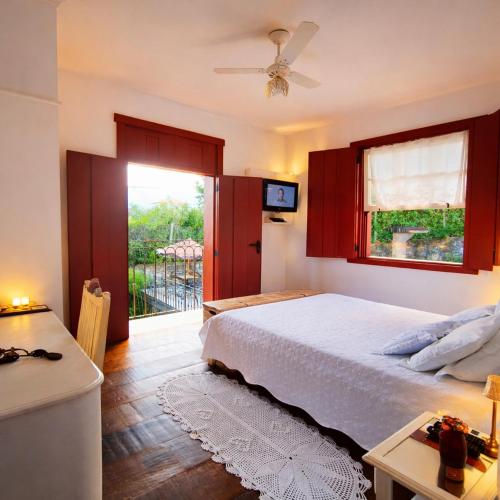 a bedroom with a bed and a table and a window at Araújo Bazilio Pousada Tiradentes in Tiradentes