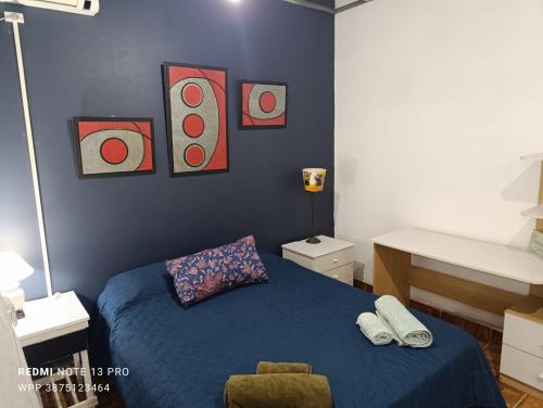 a bedroom with a bed and paintings on the wall at Casa Perla zamba in Cerrillos