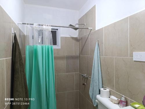 a bathroom with a shower with a green shower curtain at Casa Perla zamba in Cerrillos