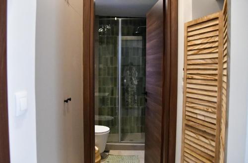 a bathroom with a toilet and a glass shower door at Everlong Boutique Home in Nea Michaniona