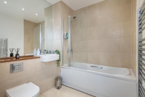 a bathroom with a tub and a toilet and a sink at Stratford Central Apartment in London