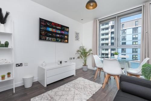 a living room with a couch and a table and chairs at Stratford Central Apartment in London