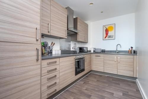 a kitchen with wooden cabinets and stainless steel appliances at Stratford Central Apartment in London