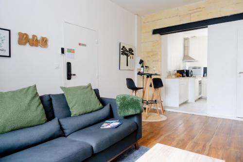 a living room with a blue couch and a kitchen at Les Libournettes - Serenity in Libourne