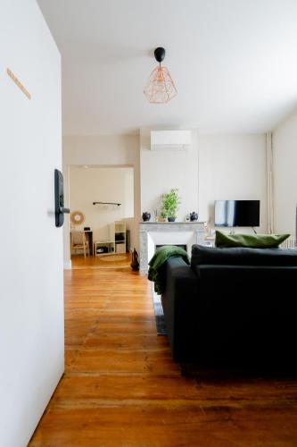 a living room with a black couch and wooden floors at Les Libournettes - Serenity in Libourne