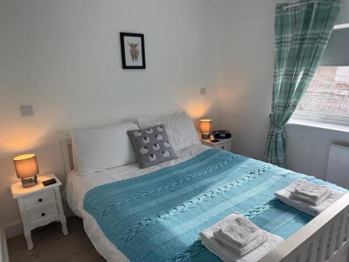 a bedroom with a bed with a blue blanket and a window at TomaX Garden Cabin Free Parking in Inverness