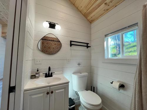a white bathroom with a toilet and a sink at Yosemite Chalet, Spacious Tiny Home with Mountain Views! in Coarsegold