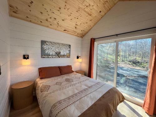 a bedroom with a bed and a large window at Yosemite Chalet, Spacious Tiny Home with Mountain Views! in Coarsegold