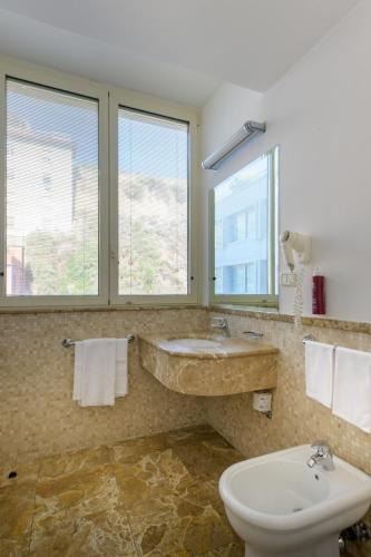 a bathroom with a sink and a toilet and windows at Hotel Royal Continental in Naples