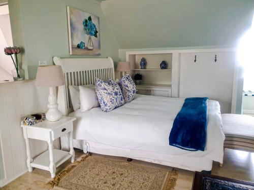 a bedroom with a large white bed with blue pillows at Turquoise Loft, Noordhoek, Cape Town in Good Hope