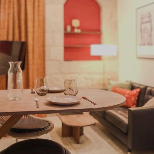 a wooden table with a plate and wine glasses on it at City Centre Gem - Machne Yehuda in Jerusalem