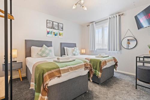 a bedroom with two beds and a tv at Spacious White House with parking, garden, Wi-Fi in Telford