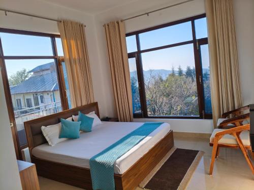 a bedroom with a bed and large windows at AeroVale Lodge I Mountain View Stay Near Landing Site Bir Billing in Bīr