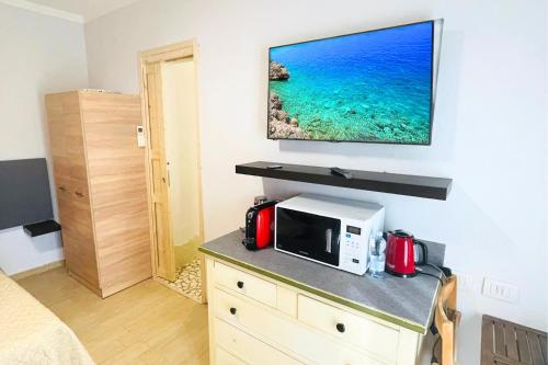 a room with a microwave and a tv on a wall at Vicino Aeroporto - Orange Marina Room in Olbia