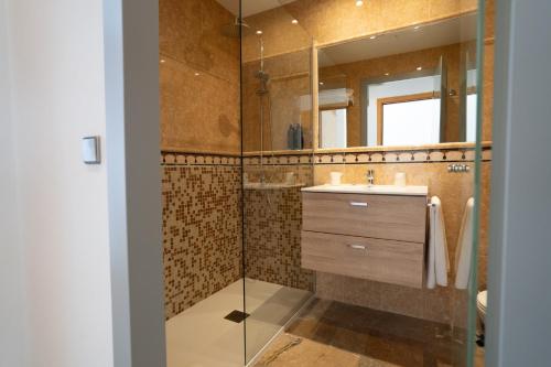 a bathroom with a shower with a sink and a mirror at Hotel Port Sitges in Sitges