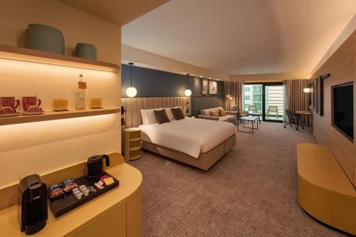 a hotel room with a bed and a living room at voco Malta by IHG in St. Julianʼs