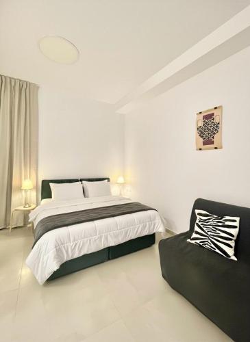 a white bedroom with a bed and a couch at Nachlaot Gem - Bright, Central and Cozy in Jerusalem