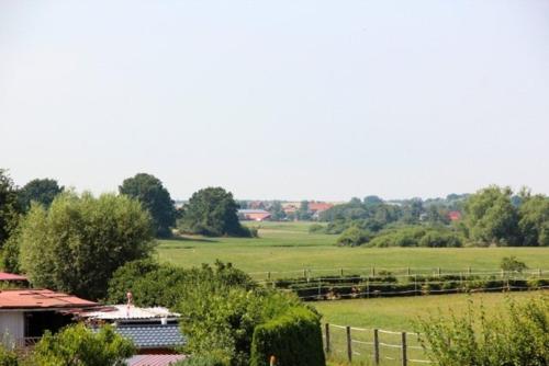 a view of a field with a fence and trees at Am Wiesenblick 2 Pers in Röbel